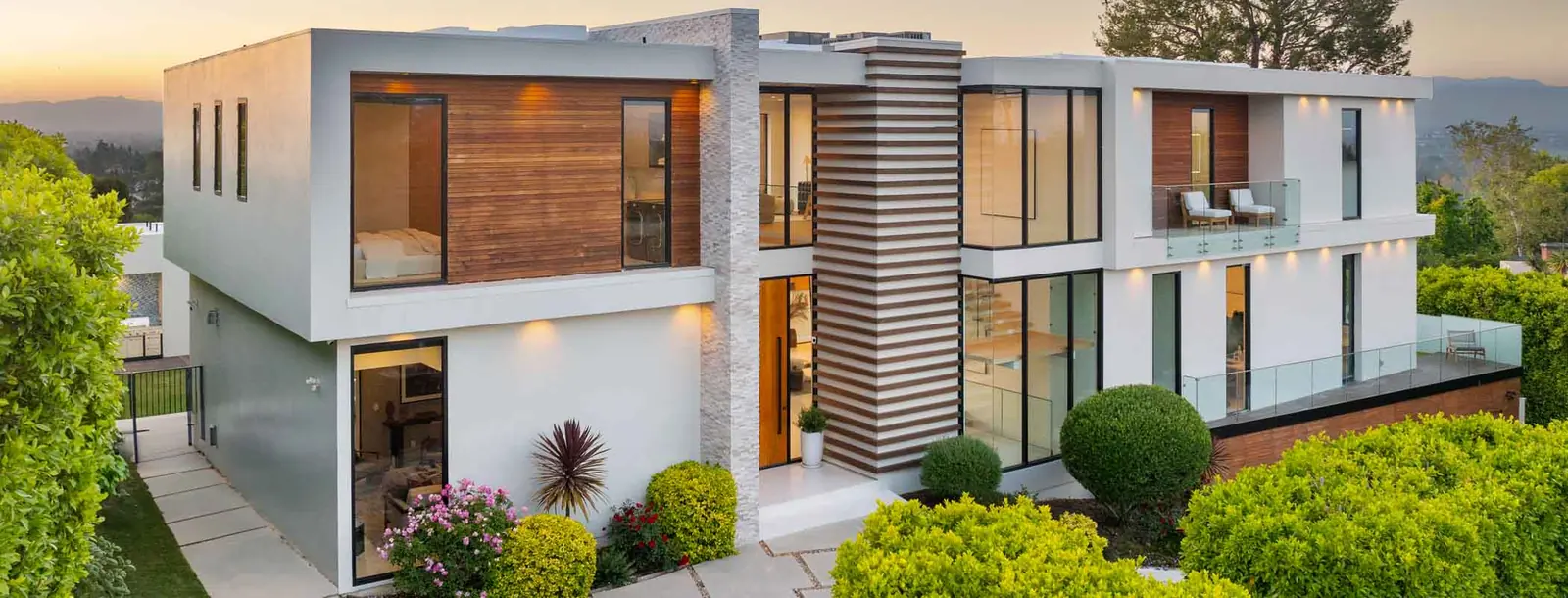 Moderne witte villa met houten accenten en grote ramen, in de avond