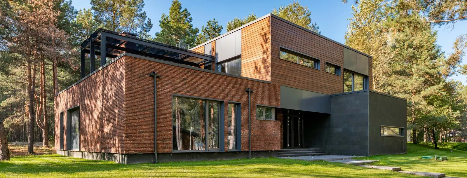 Moderne bakstenen woning met grote ramen, tussen de bomen