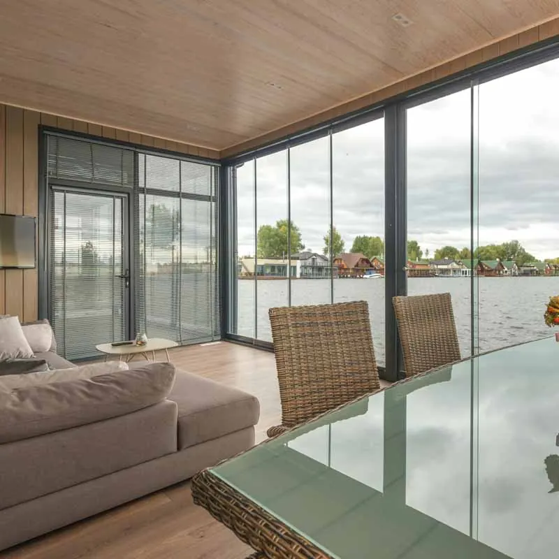 Woonkamer met een donkere glaswand en uitzicht op het water