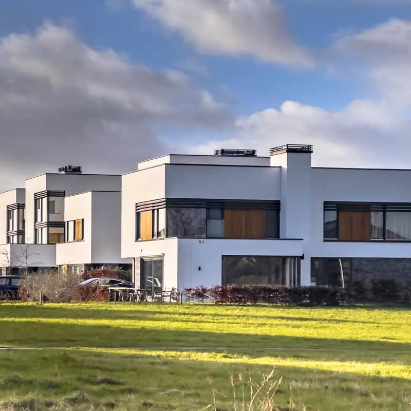 Witte rijwoningen met antraciet kozijnen aan een grasveld